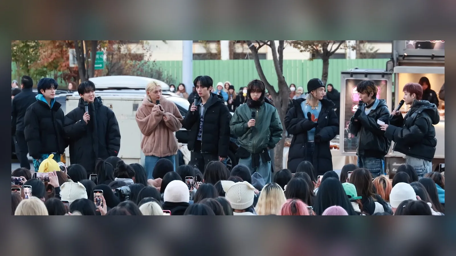 2023년 스트레이 키즈가 야외 미니 팬미팅에서 팬들 앞에 나란히 서서 마이크로 이야기하는 모습